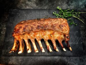 Delicious grilled spare ribs served with fresh herbs on a stone surface.