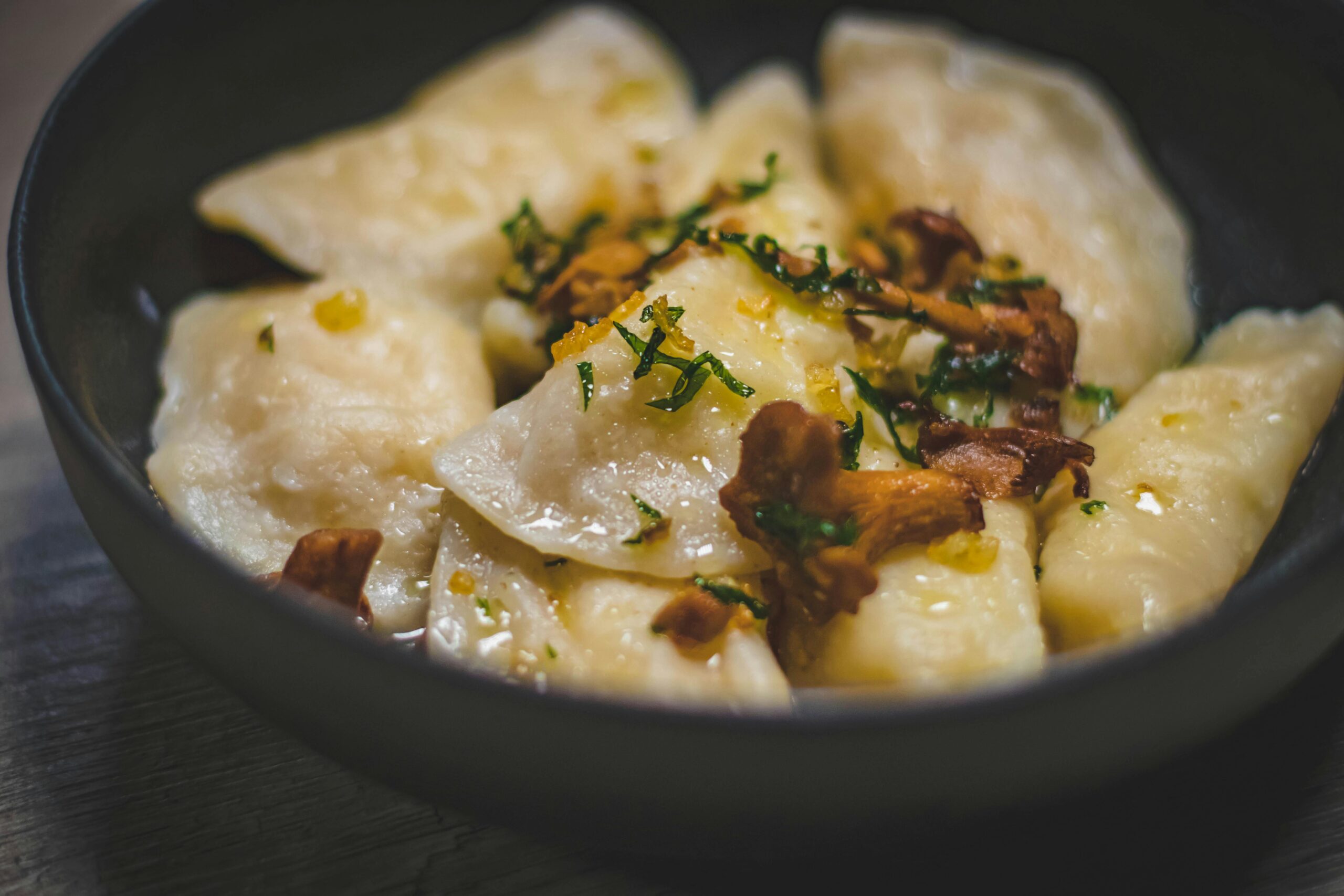 Appetizing pierogi with chanterelle mushrooms and herbs, captured indoors for a gourmet presentation.