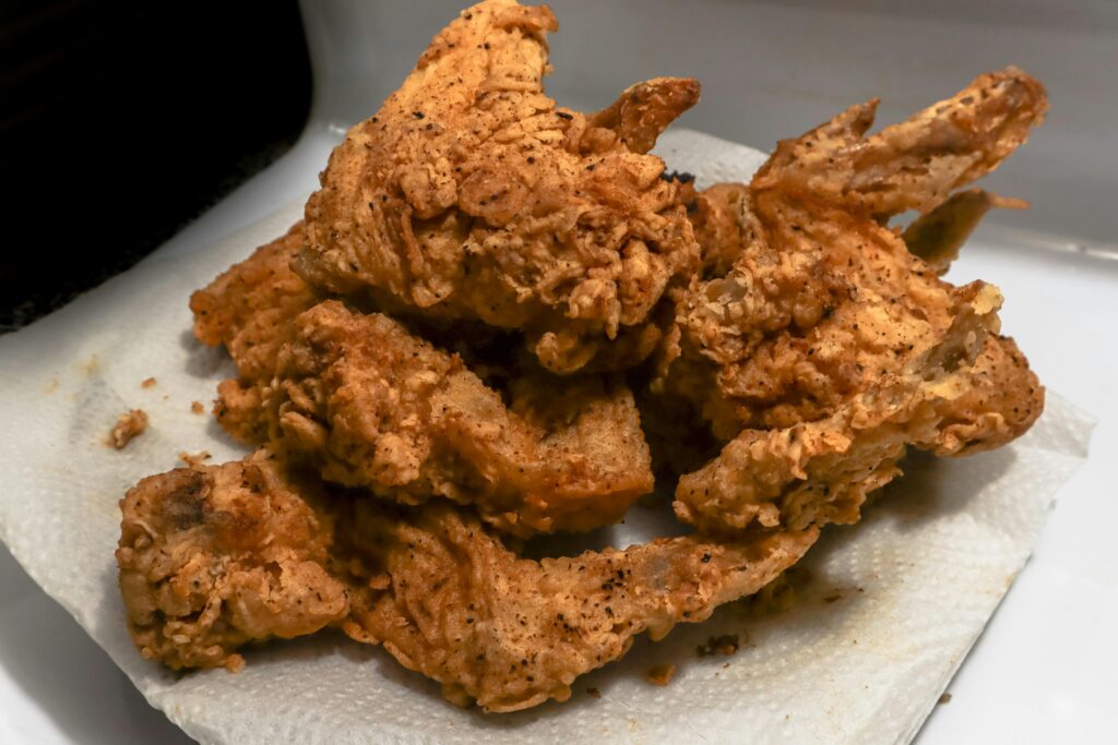 Golden brown fried chicken wings on a paper towel, showcasing a delicious, crispy texture.